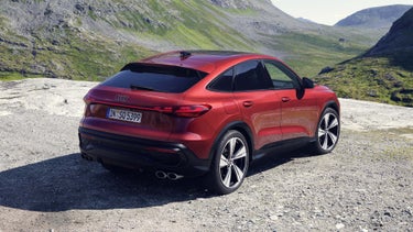 Schräge Heckansicht des SQ5 Sportback in der roten Edition One mit Akzenten in schwarz. Im Hintergrund eine bergige Landschaft.
