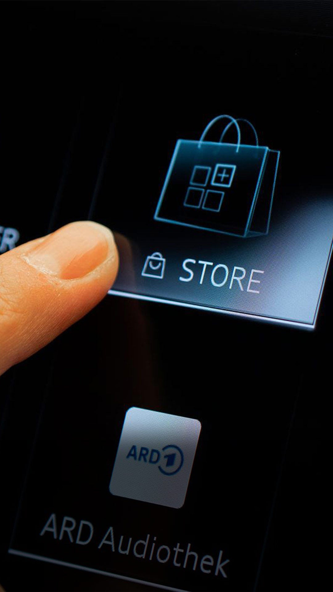 Finger tippt auf den Store-Button im Audi Infotainmentsystem neben den Apps Kalender, Spotify und ARD Audiothek.
