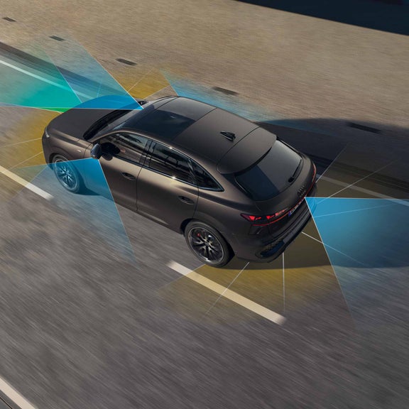 Q3 Sportback uz ceļa – redzami adaptīvās vadītāja palīgsistēmas joslas robežu marķējumi zilā un dzeltenā krāsā.