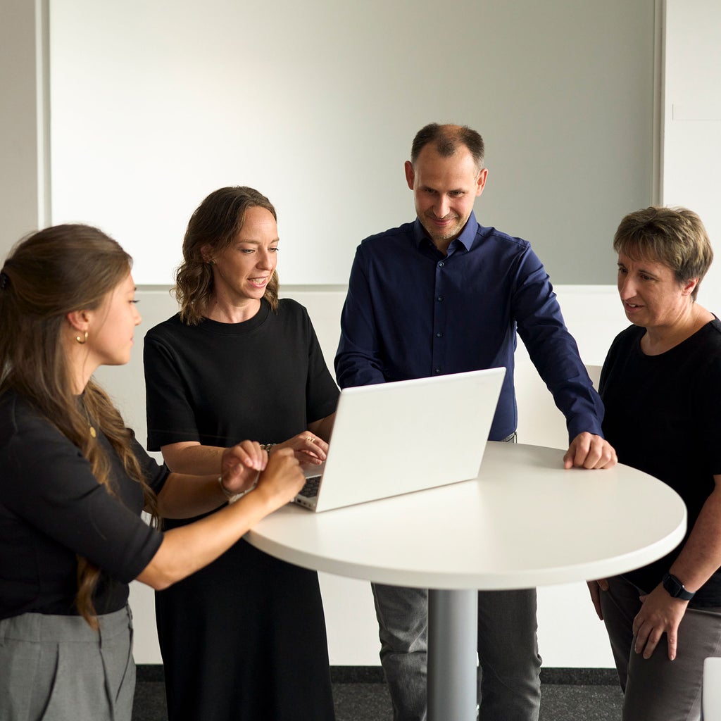 Melanie Limmer spricht mit Kollegen und zeigt ihnen etwas auf einem Laptop
