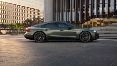 Seitenansicht des Audi RS e-tron GT performance, vor einem modernen Bürogebäude stehend.