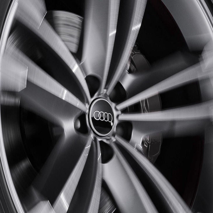 Nahaufnahme einer rotierenden Audi-Felge mit sichtbarem Markenlogo in der Radnabenmitte.