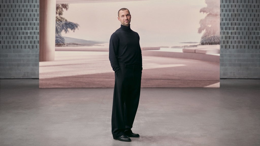 Porträt von Andrés Reisinger vor einem Bildschirm, der eine virtuelle Welt zeigt.