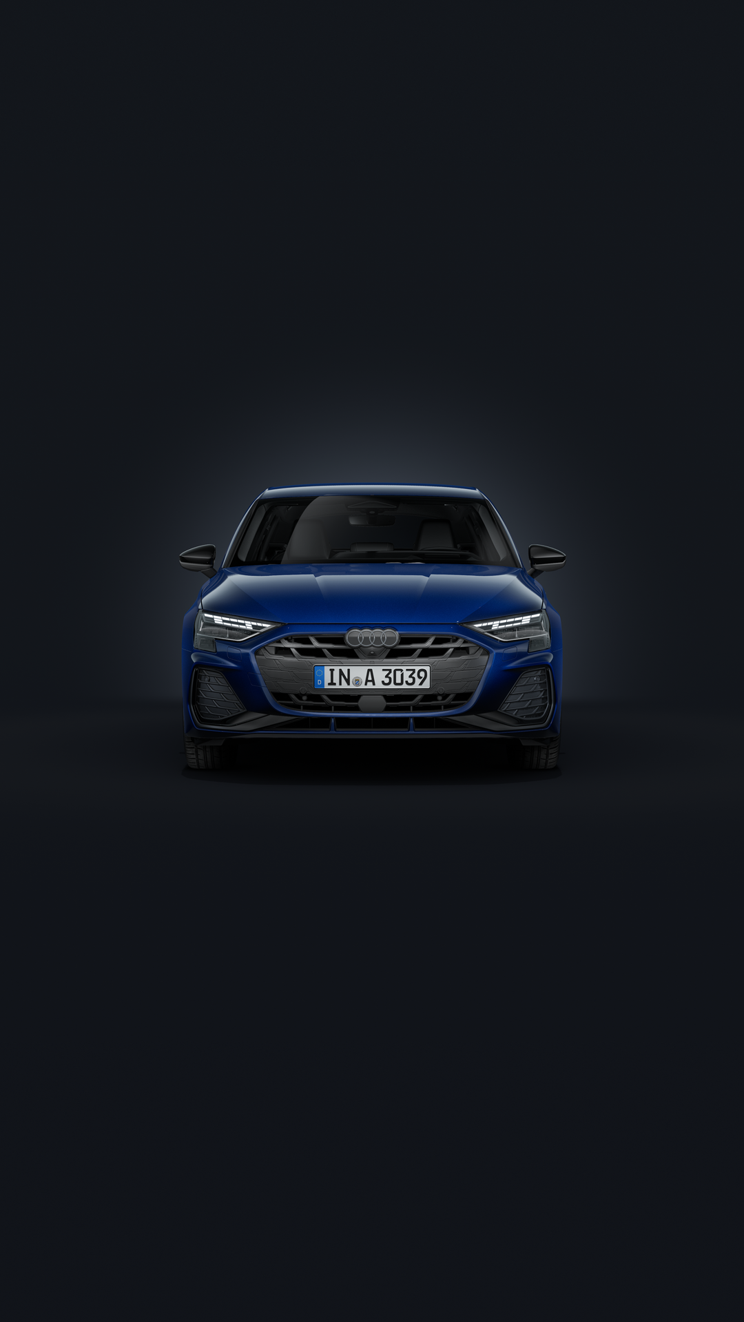 De Audi A3 Sportback staat tegen een donkere achtergrond en is licht naar rechts gedraaid.