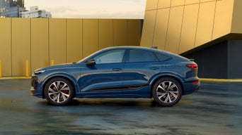 Blue SUV parked at an outdoor lot with yellow walls in the background.