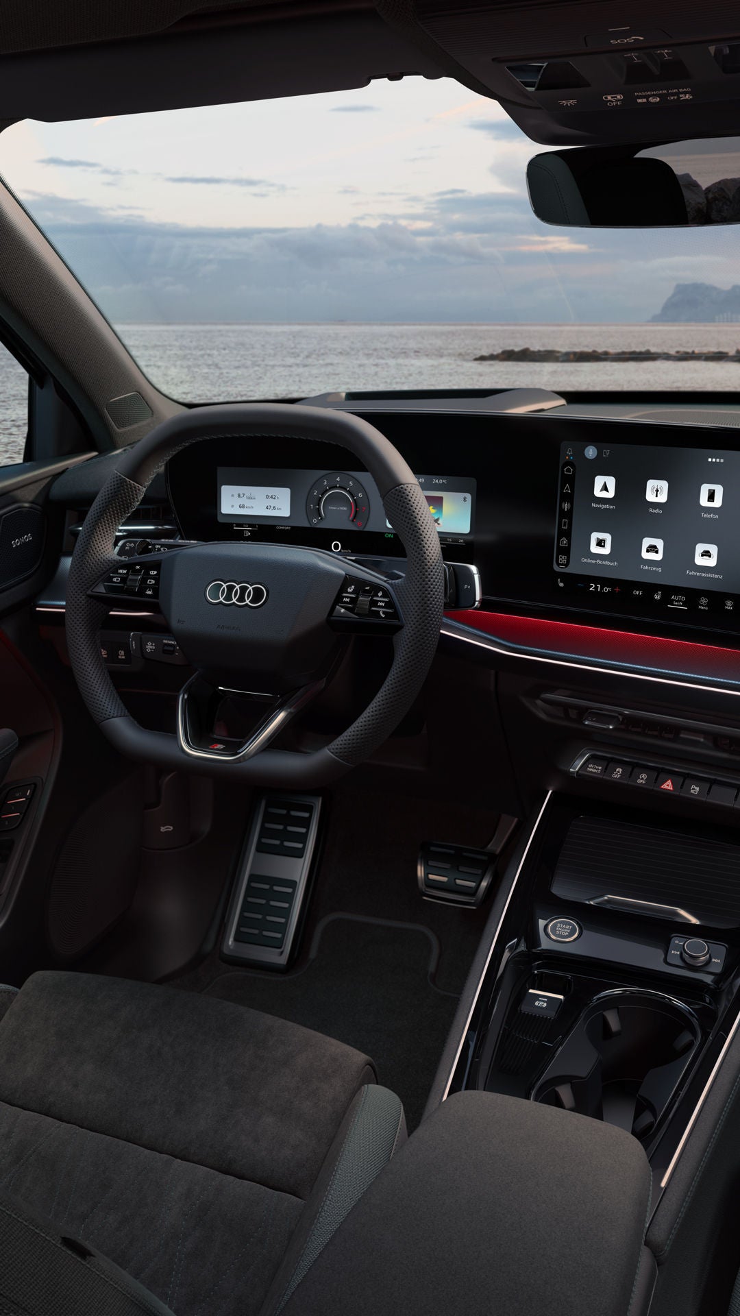 Blick von hinten auf das Cockpit des Q3 SUV mit Lenkrad, Panoramadisplay und rotem Ambiente-Lichtpaket. Durch die Frontscheibe ist das Meer zu sehen.
