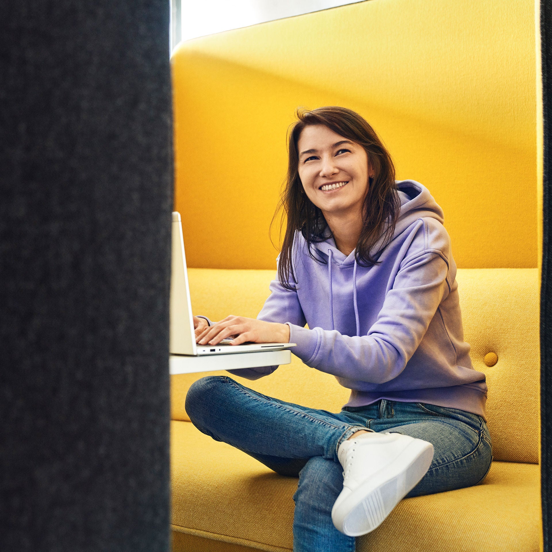 Sevgi laughs past the camera and has a laptop in front of her