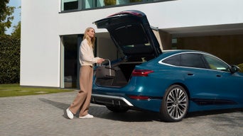 Frau steht mit einem Faltkorb mit Audi Logo vor dem Kofferraum eines Audi S6