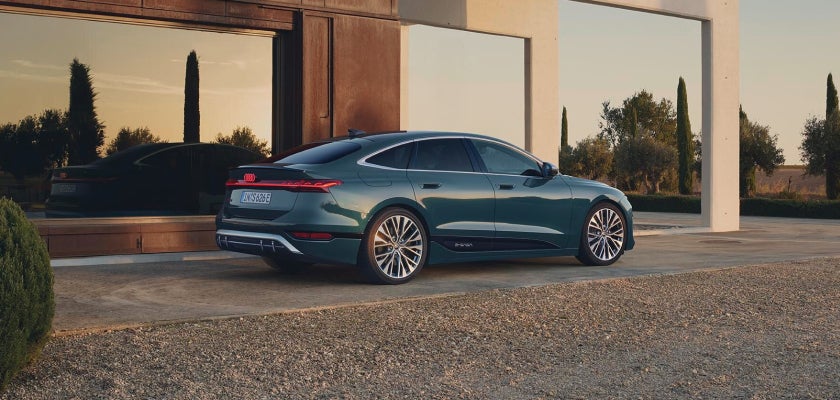 A blue electric Audi vehicle parked in front of a modern house