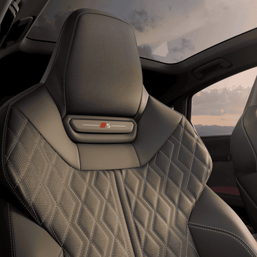 Audi car interior with steering wheel and dual dashboard screens at dusk.