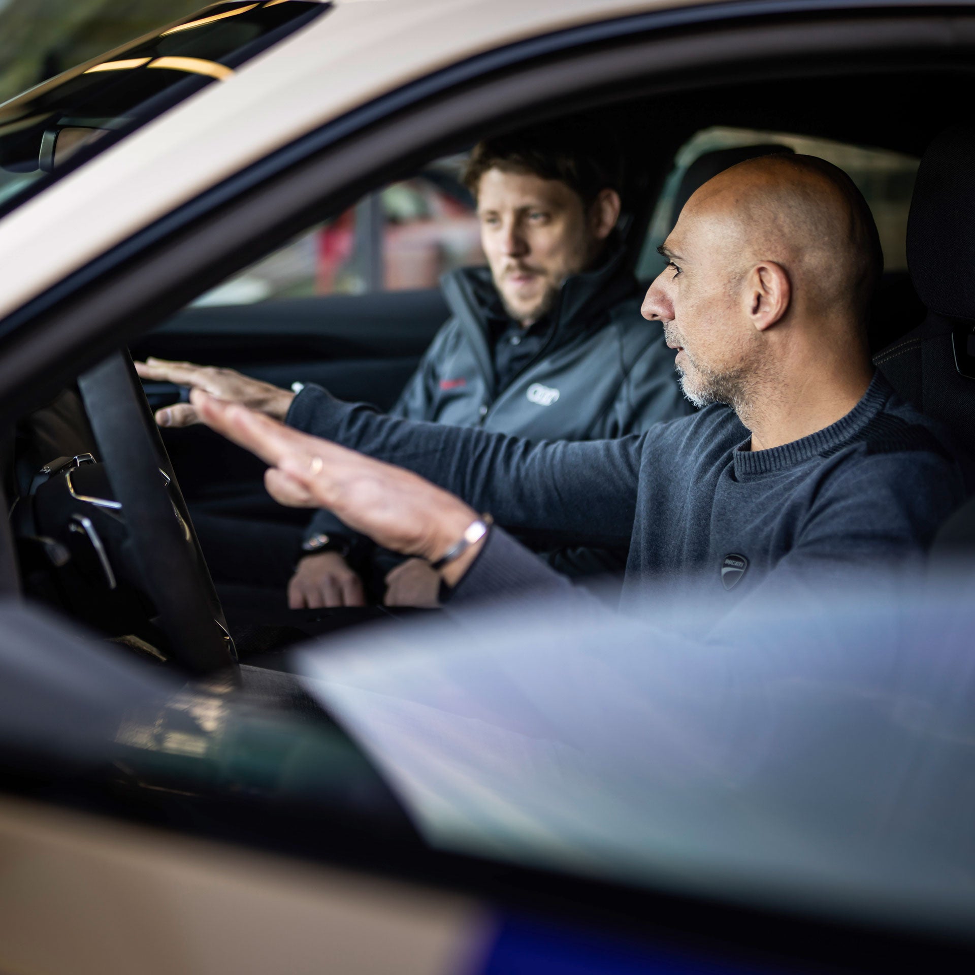 Jaan-Mattes Reiling, Technical Project Manager at Audi, and Alessandro Valia, Chief Test Driver at Ducati, sit in the Audi e-tron GT quattro