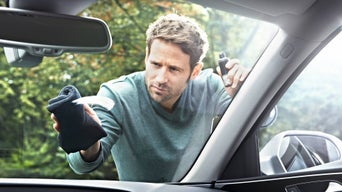 Mann tørker frontrute på bil