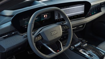 Detailansicht des Audi-Innenraums mit Lenkrad, digitalem Cockpit und breitem Infotainment-Display auf der Beifahrerseite.