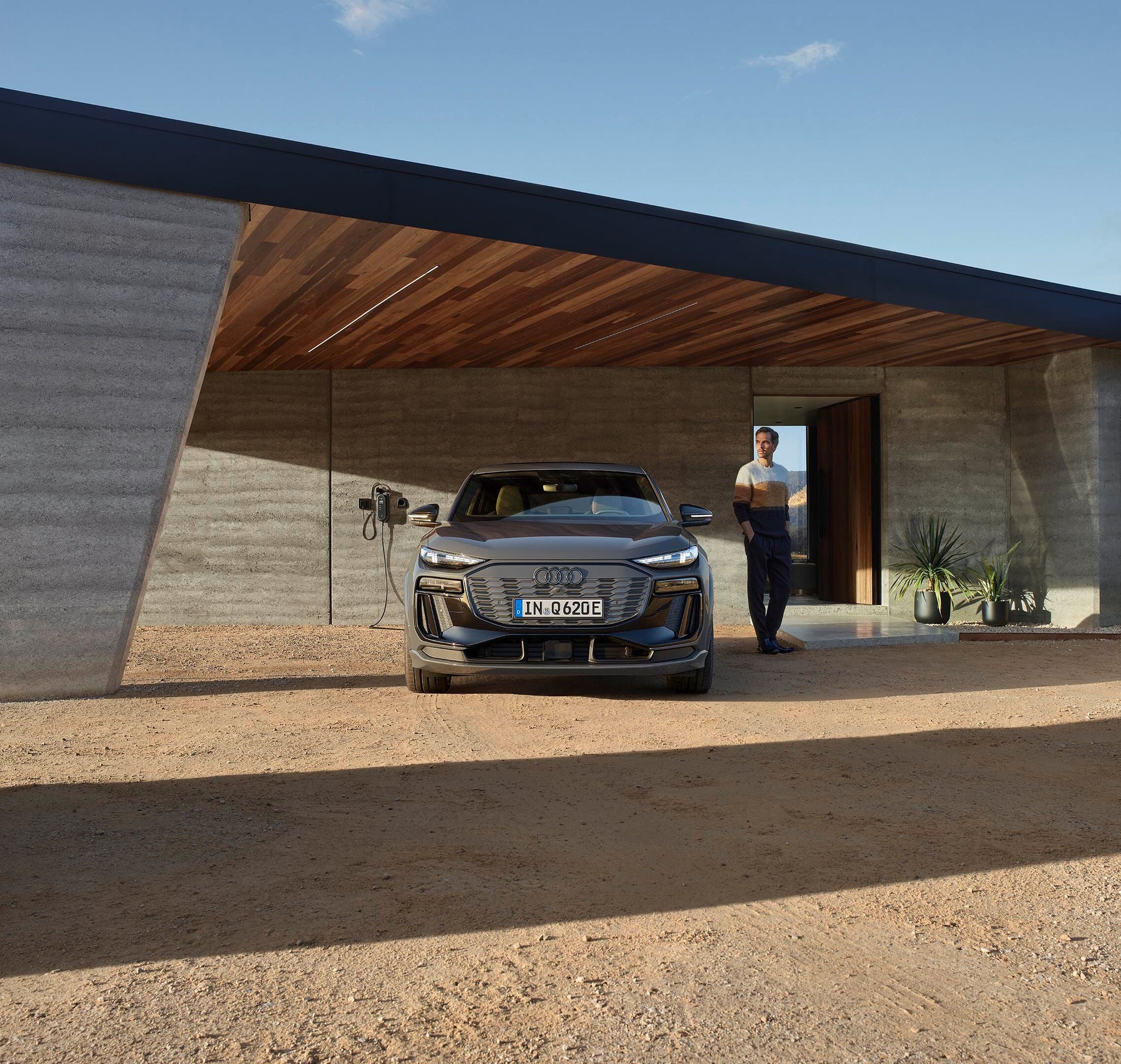 Q6 Sportback e-tron står framför ett garage, en man står bredvid