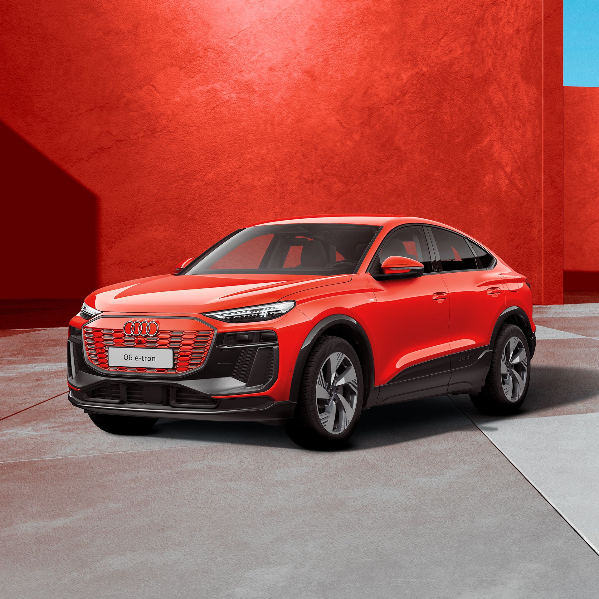 Ein roter Audi Q6 Sportback e-tron in einem hellen Studio mit grauem Boden und weichen Lichteffekten.