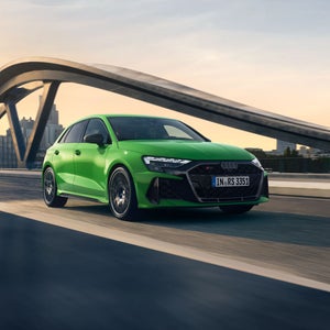 Der RS 3 Sportback von schräg vorn fährt auf einer Brücke, im Hintergrund eine Skyline.