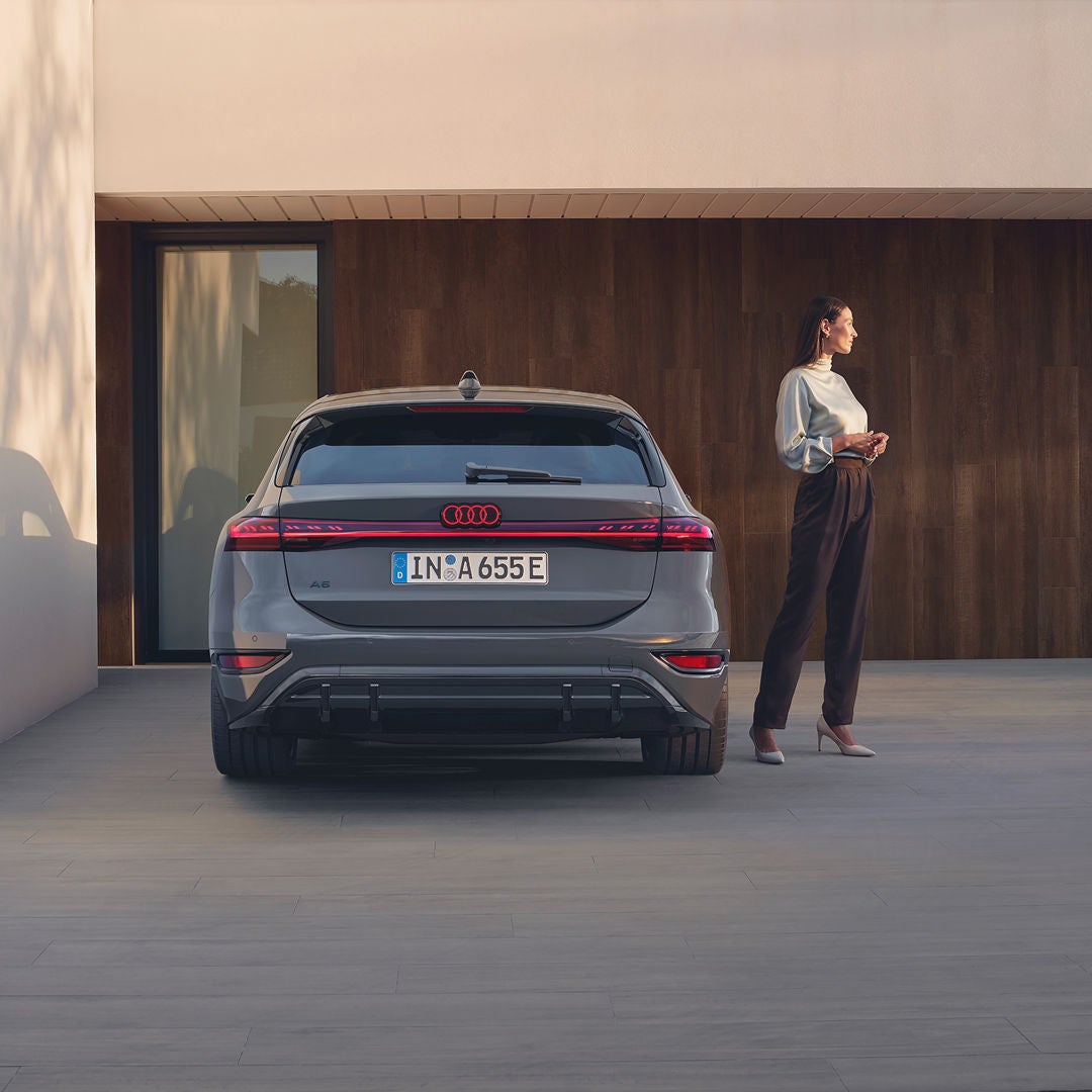 rear view of Audi vehicle parked outside modern property with lady standing next to it