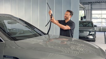 Mann hält einen Scheibenwischer an einen Audi