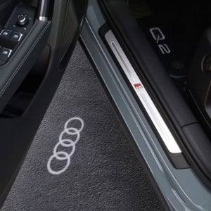 An open Audi Q2 door with light casting the Audi logo on the floor