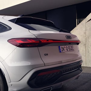Der Q5 Sportback e-hybrid mit Nahaufnahme auf die linke Heckleuchte und die Schlusslichtsignatur via OLED-Technologie.
