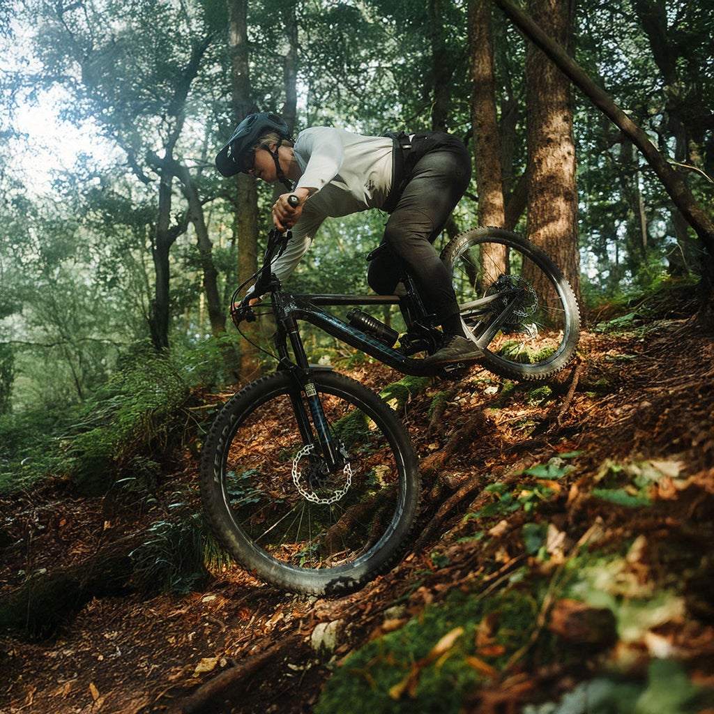 Lissi Lanz fährt mit ihrem Mountainbike durch einen Wald einen Berg herunter