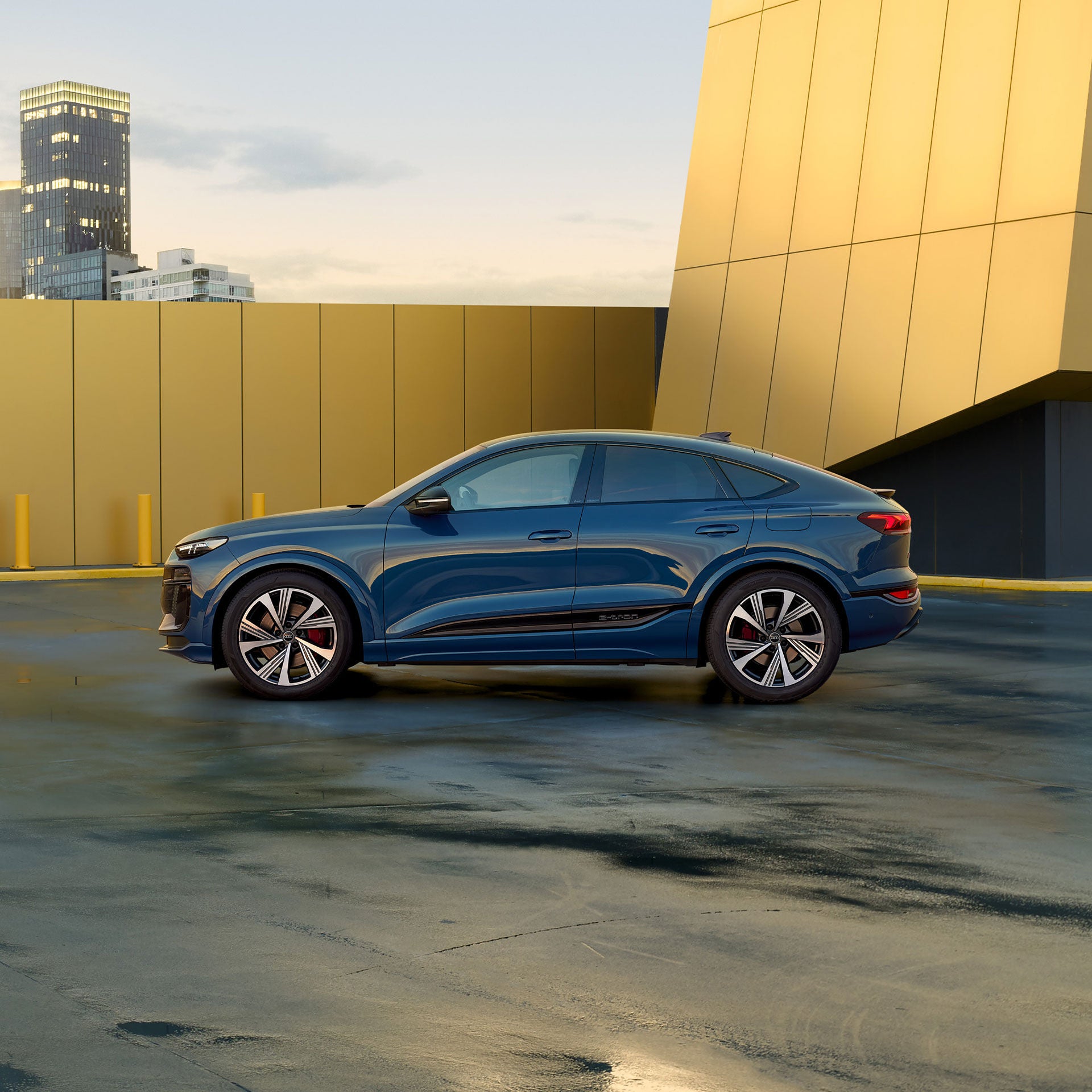 Ein blauer Audi SQ6 Sportback e-tron mit sportlichem Design steht vor einem modernen, goldfarbenen Gebäude bei Tageslicht.