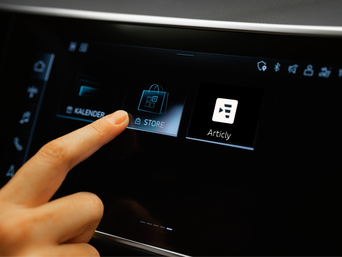 Finger tippt auf die Store-App im Audi Display, daneben ist die App „Articly“ sichtbar, im Hintergrund dunkle Anzeige und links die App Kalender.