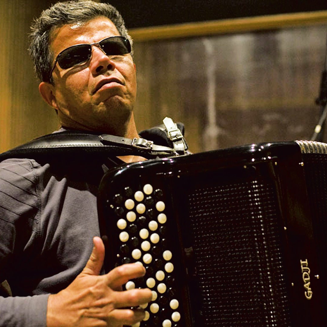 Mann mit Sonnenbrille spielt schwarzes Akkordeon mit weißen Knöpfen in einem Studio.