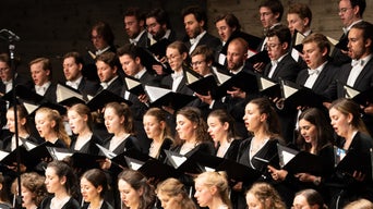 Chor der Audi Jugendchorakademie bei einer Aufführung: junge Sängerinnen und Sänger in Konzertkleidung mit Noten in der Hand.