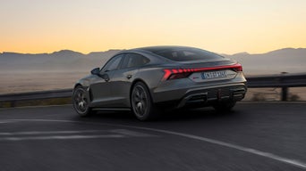 Der RS e-tron GT fährt auf einer kurvigen Gebirgsstraße bei Dämmerung.