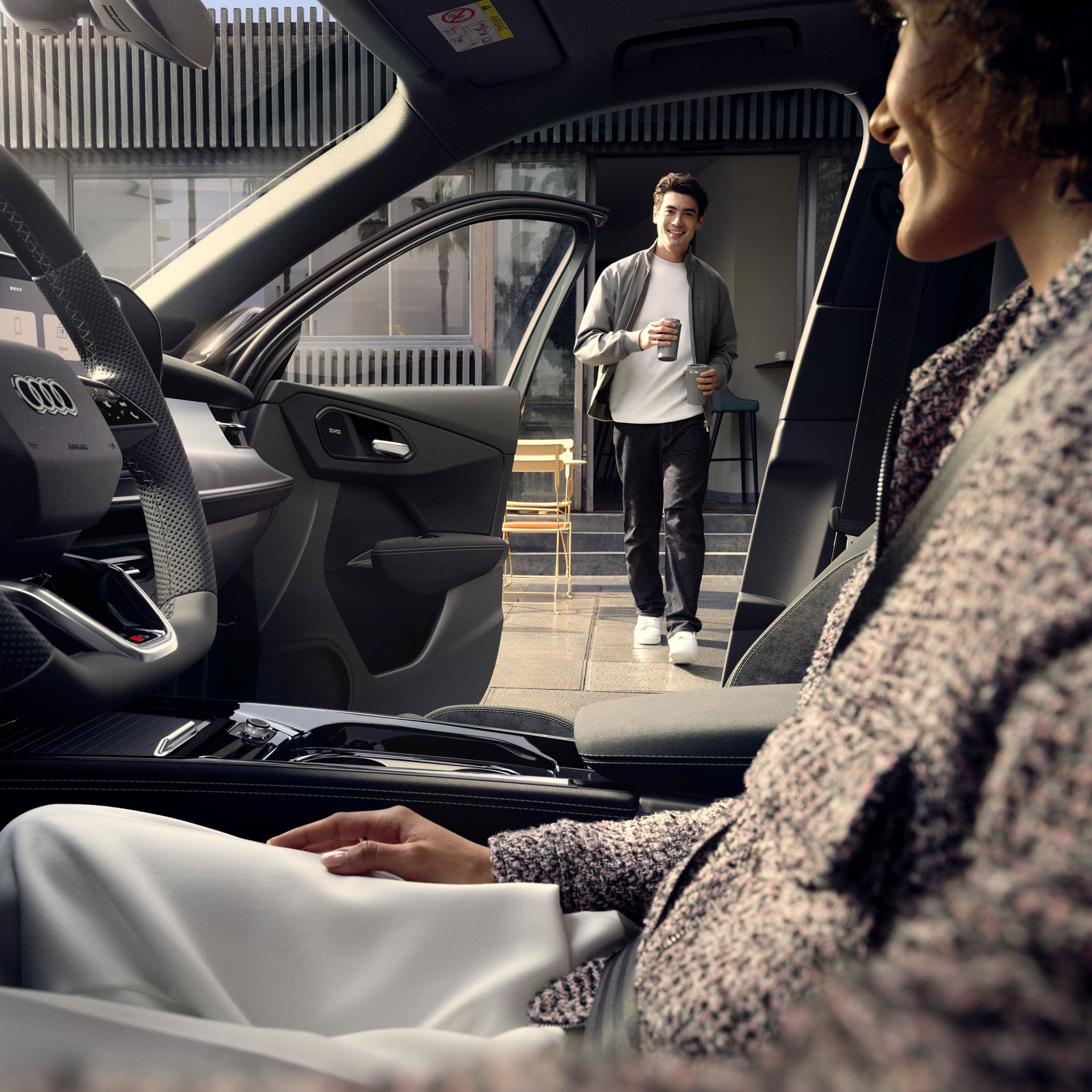 Frau lädt braunen Audi e-tron vor Holzhaus in bergiger Winterlandschaft.