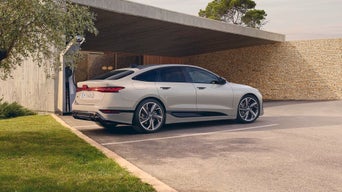 A6 Sportback e-tron parked outside a modern home under a covered area, with a minimalist stone wall in the background.