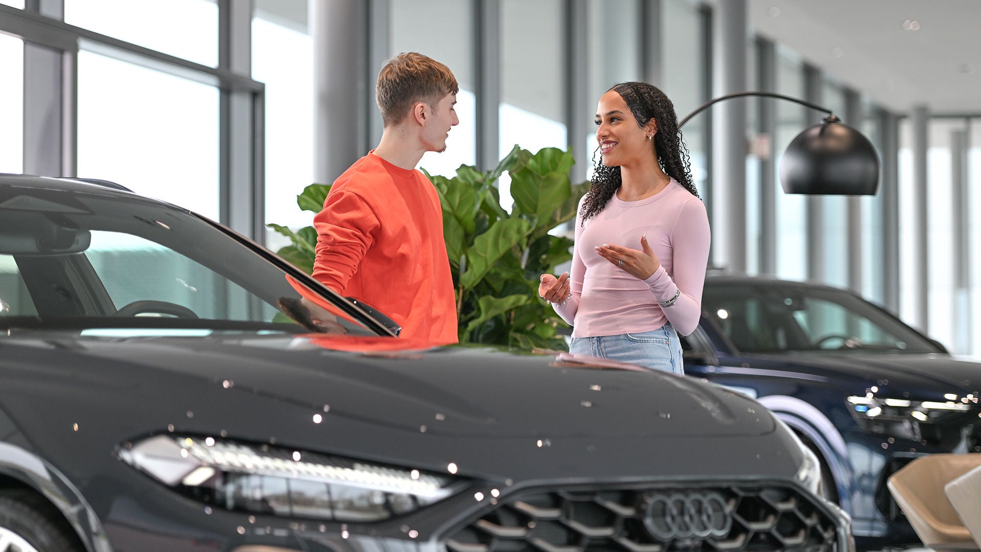 Junger Mann lehnt entspannt am Heck eines Audi
