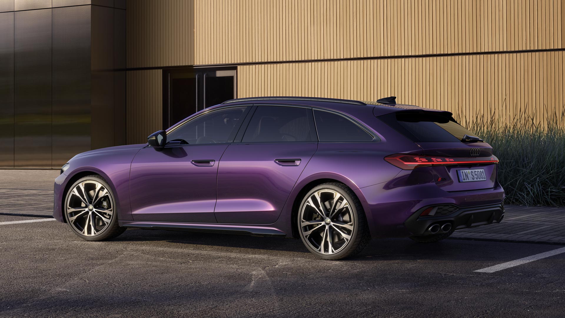 Der S5 Avant in Merlin Perleffekt steht auf einem Parkplatz vor einem Gebäude, seitlich fotografiert.