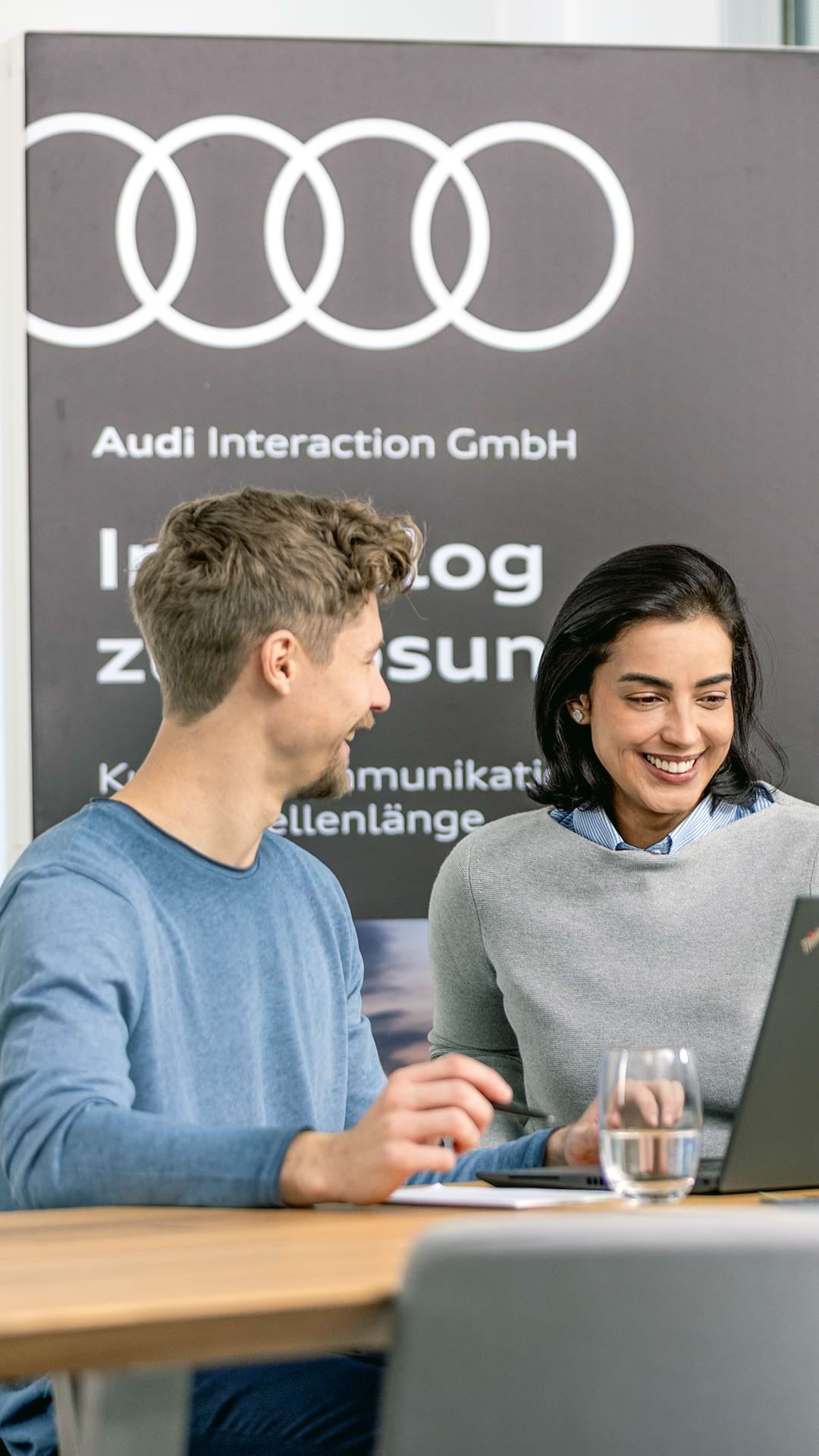 Three employees behind a desk looking at a laptop screen