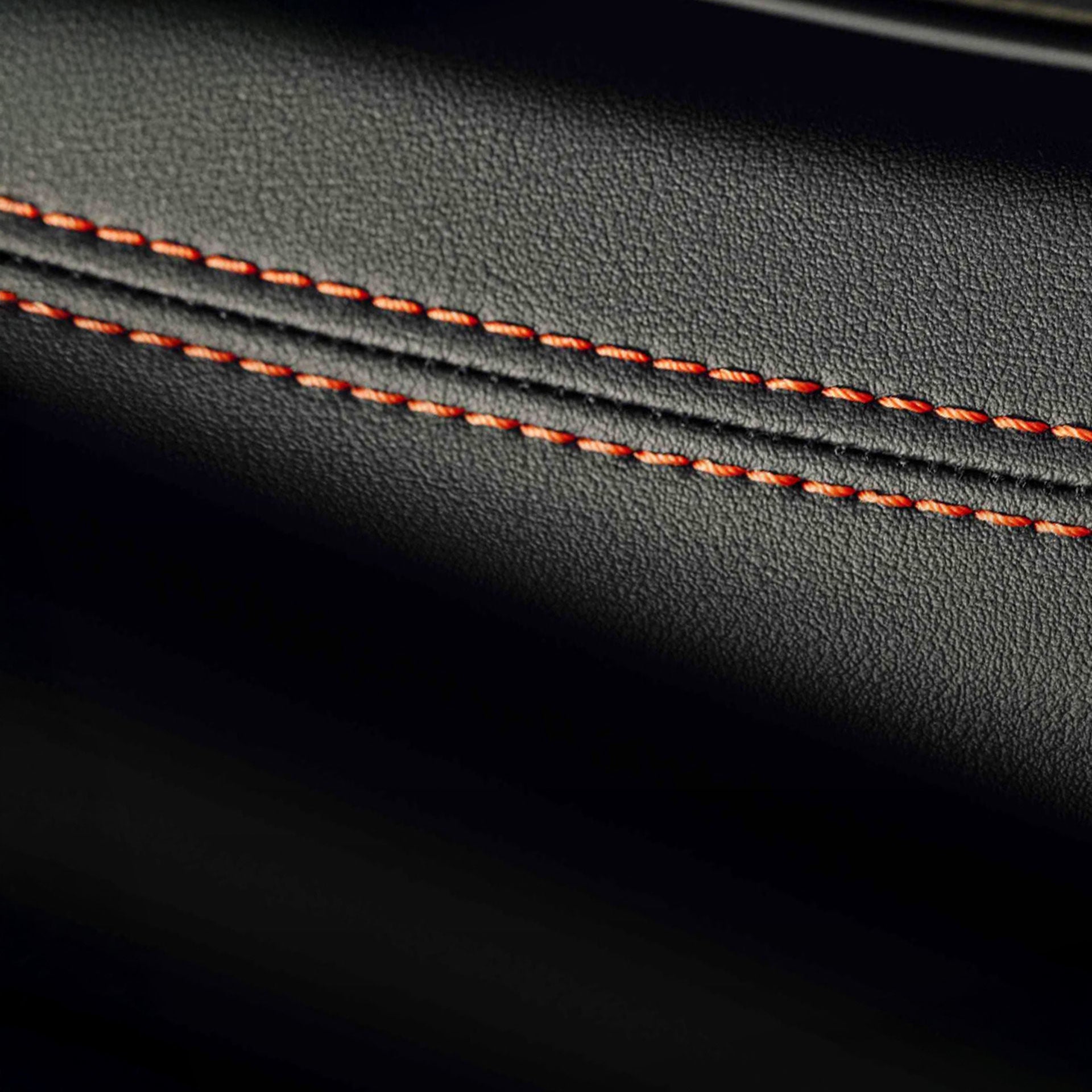 Detailaufnahme einer Naht eines Ledersitzes mit orangenen Fäden