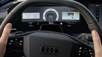 Close-up of the steering wheel and the driver display behind it while driving.