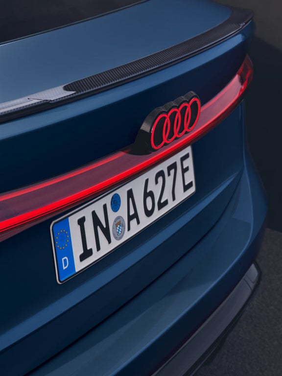 Heckansicht eines blauen Audi A6 Sportback e-tron mit Carbon-Spoiler und rot leuchtendem Rücklicht.