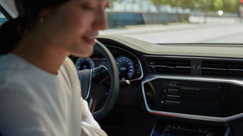 Close-up auf das vordere Interieur auf der Fahrerseite, die Fahrerin sucht nach etwas.