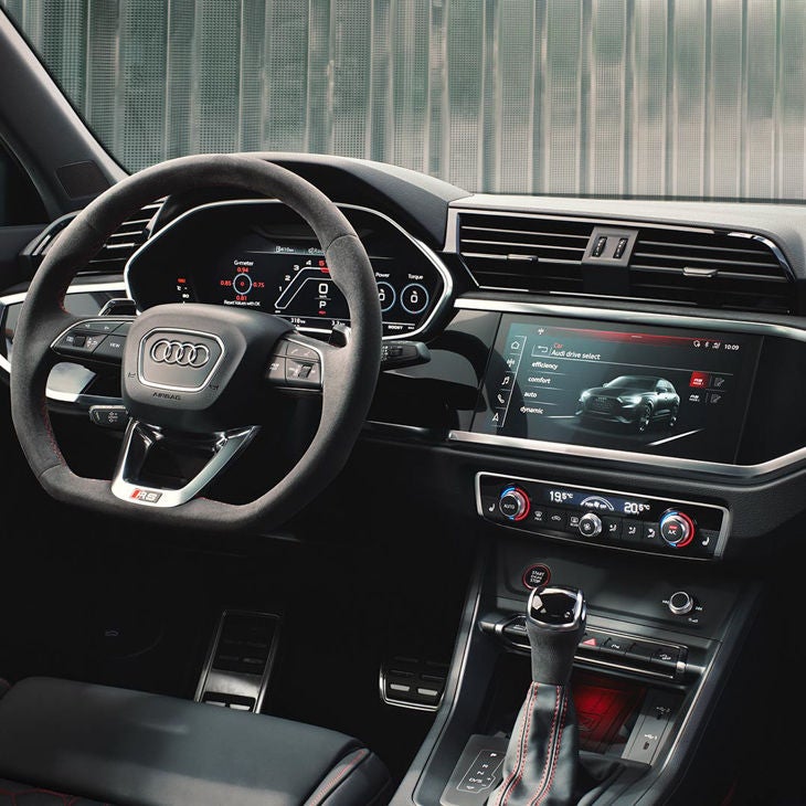  Interior view of a car with steering wheel, dashboard, and infotainment screen.
