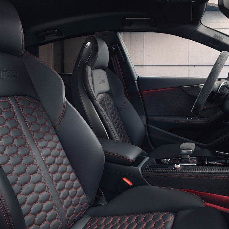 Car's interior with black leather sport seats and red stitching.