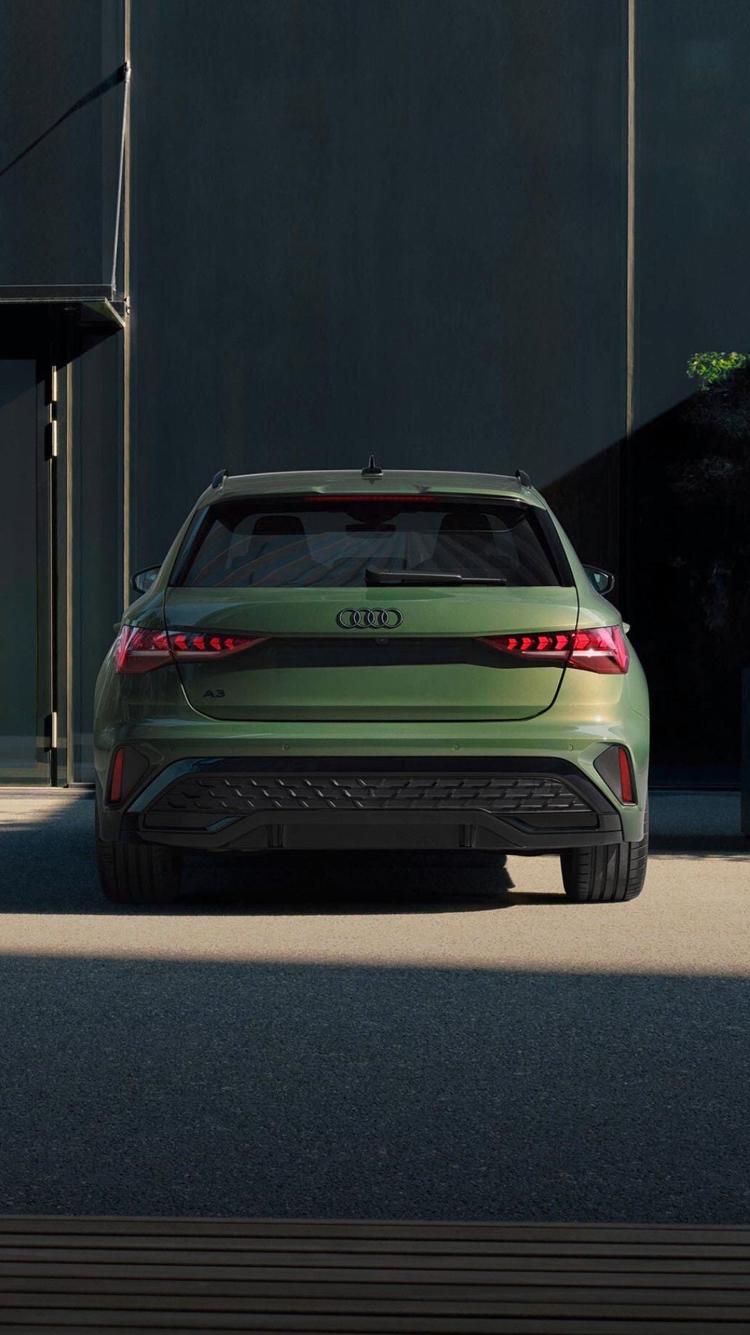 rear view of green Audi A3 parked outside modern building