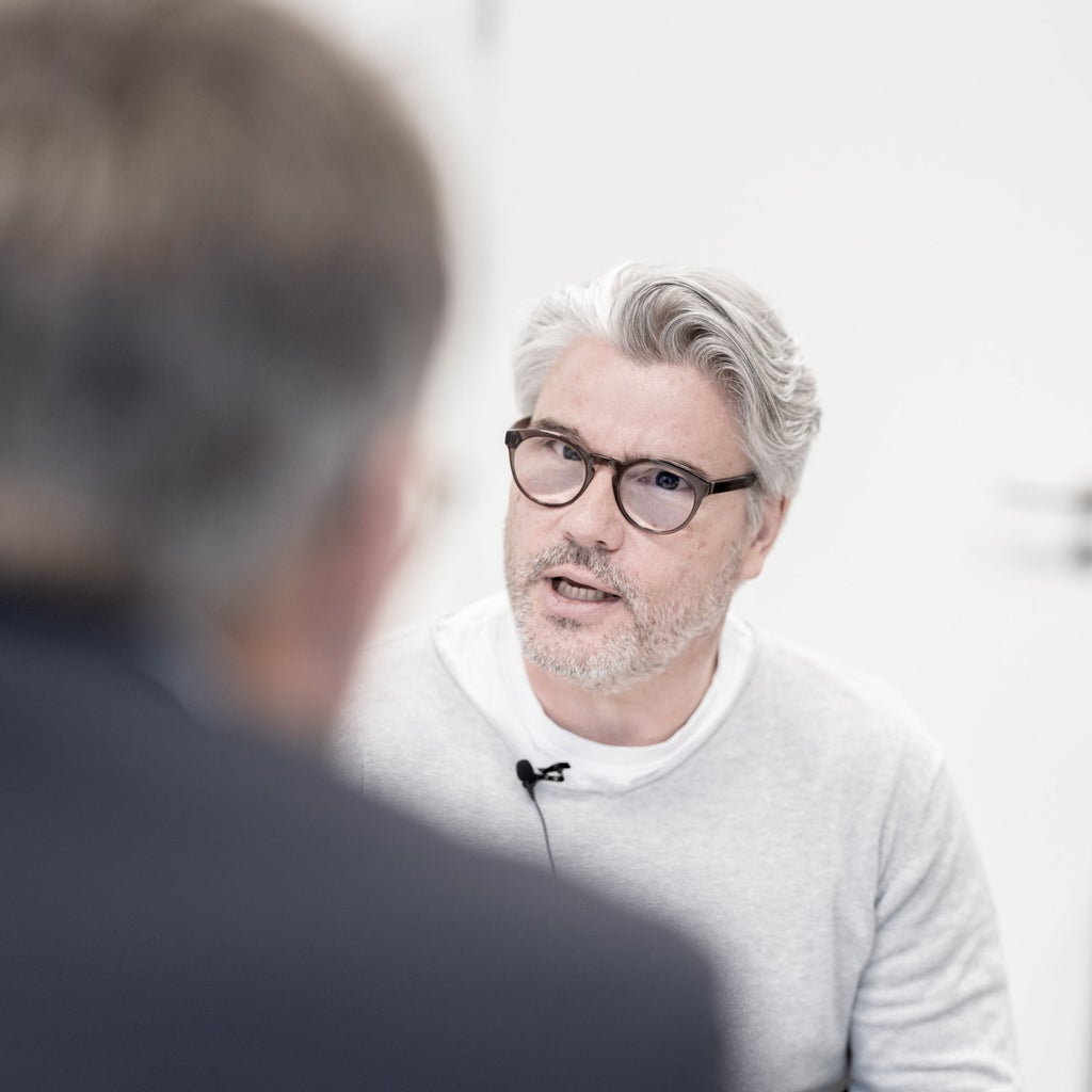 Heiko Schmidt talks to a person sitting with their back to the camera