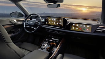 Blick ins Audi-Cockpit mit großem Display und Navigationskarte bei Sonnenuntergang.