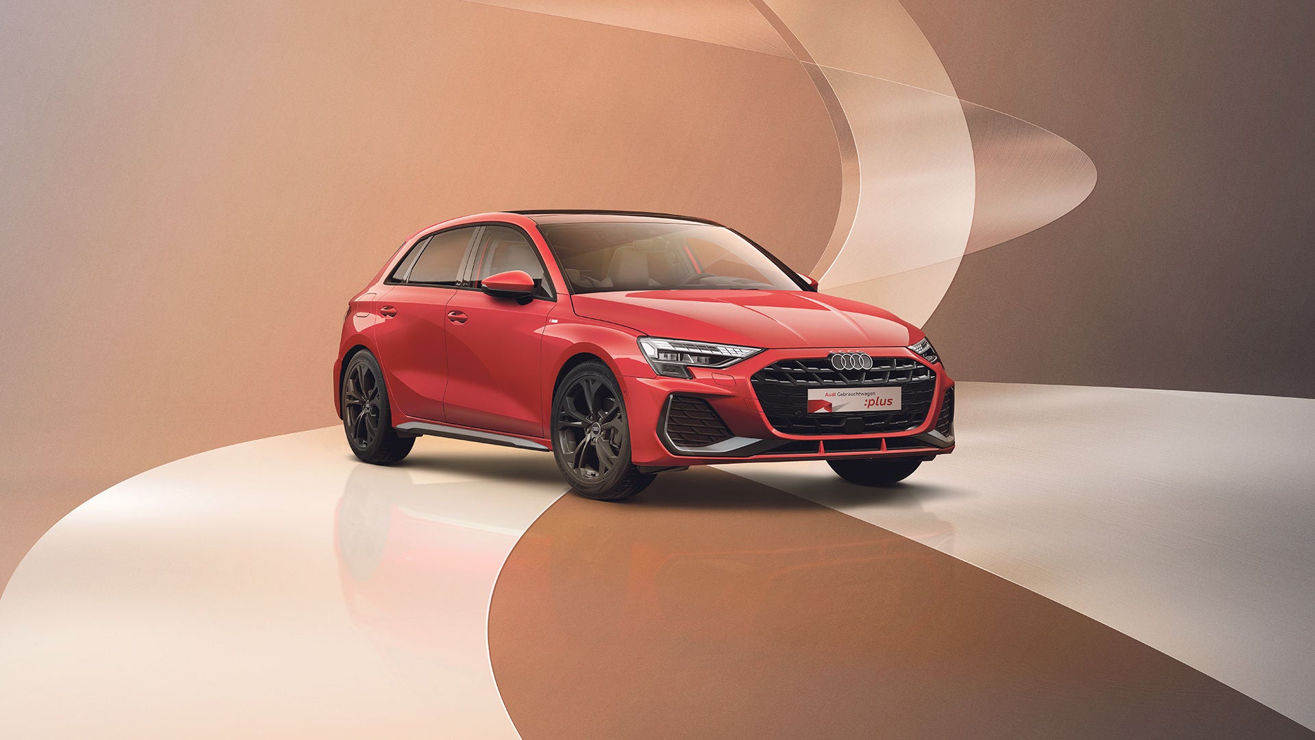 Ein roter Audi A3 steht auf einem modernen, bräunlichen Untergrund mit geschwungenen Dekoelementen.