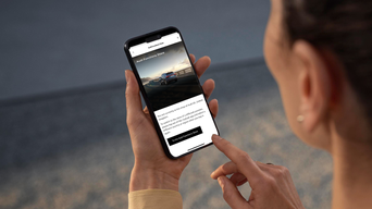 A person browsing the Audi Functions Store app on a smartphone, exploring features with a car image in the background.