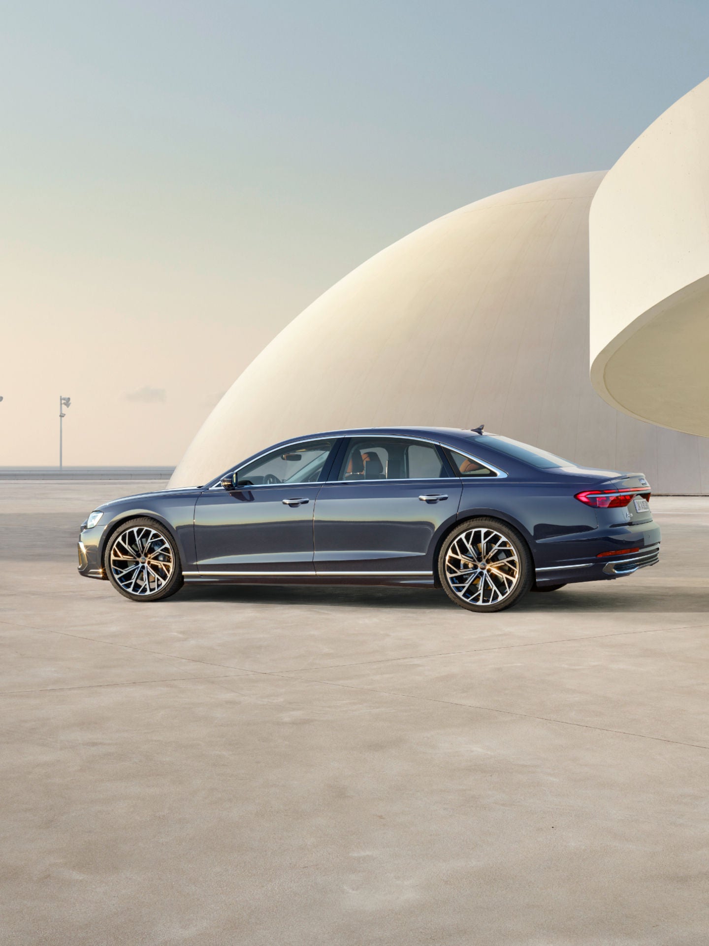 A car parked outside a modern building with a person standing nearby.