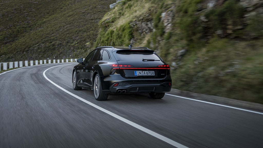 The back of the all-new A6 Avant driving down a road.
