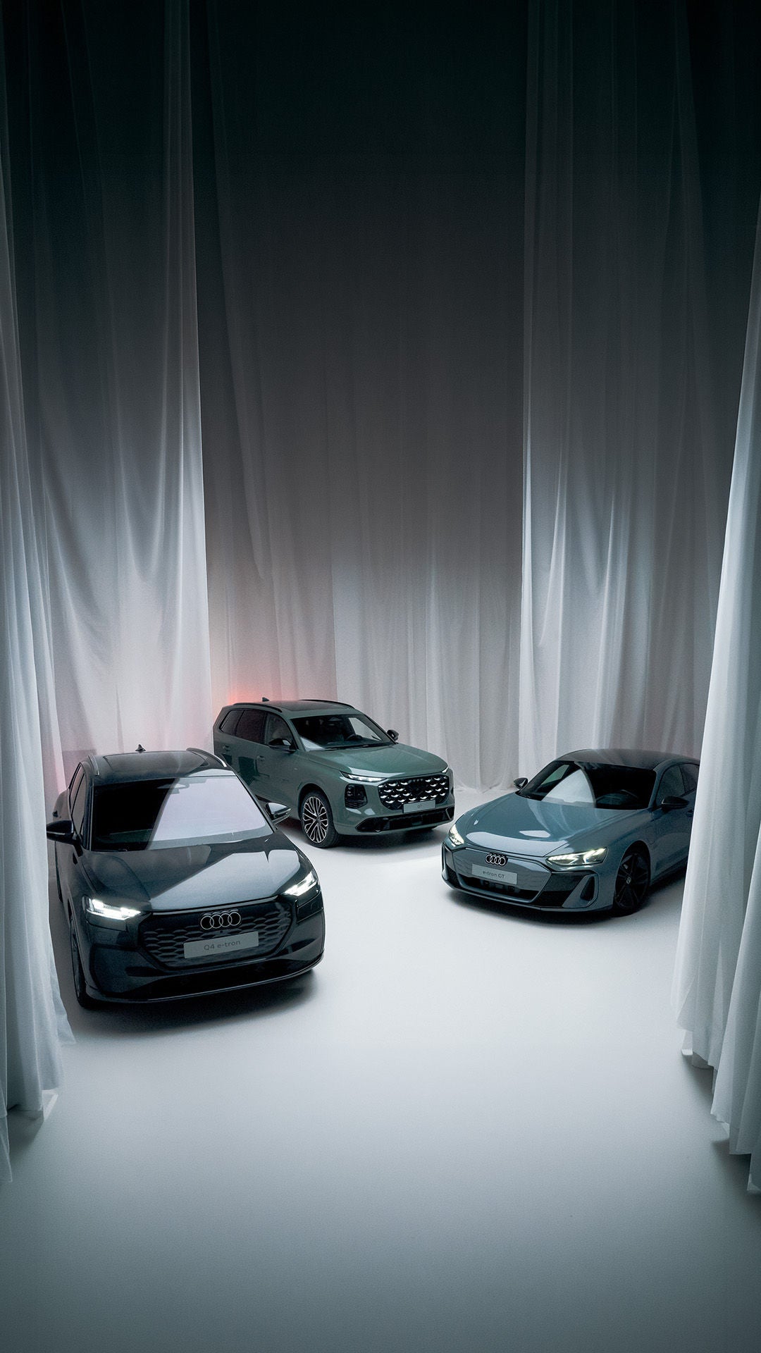 Dreiviertel-/Frontansicht eines Q4 e-tron, Q7 und eines e-tron GT in neutraler Studioumgebung.