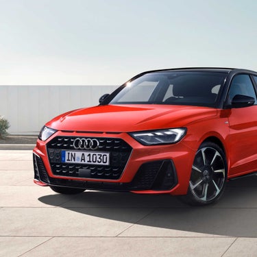 Red Audi A1 Sportback car parked outdoors with clear sky in the background.